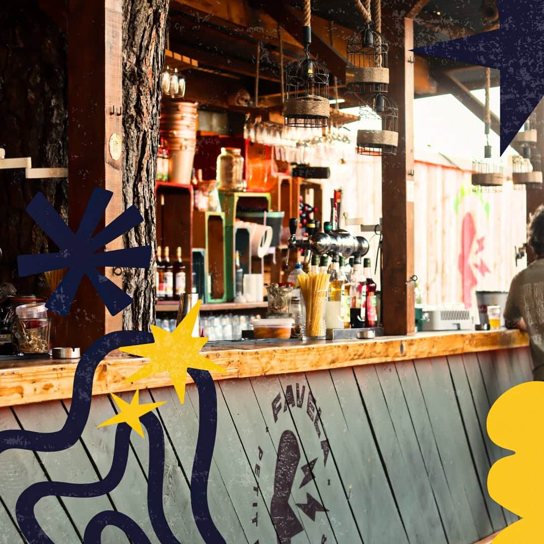 Bar rustique Favela Petit : comptoir en bois, tireuses à bière et décorations graphiques avec lampes cages.