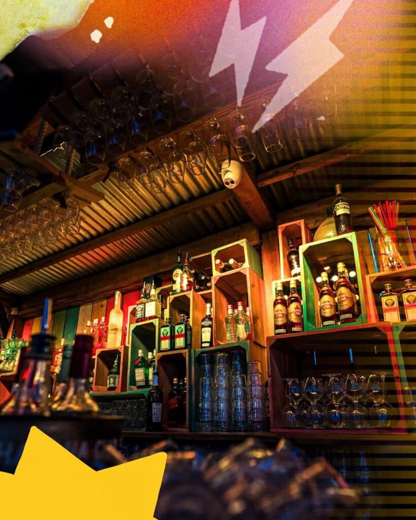 Bar de Plage Rustique avec Rhum Havana Club et Spiritueux Bar rustique, bouteilles Havana Club et Jägermeister sur étagères en bois sous un toit en tôle ondulée.