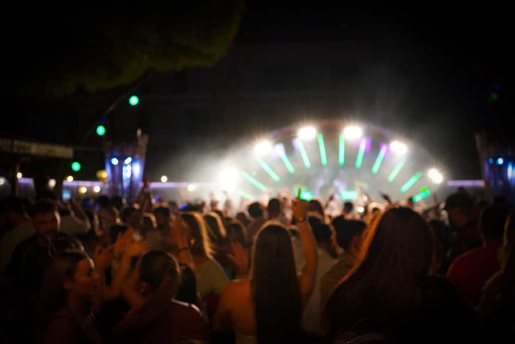 Festival de musique : ambiance nocturne et scène lumineuse Foule en liesse dansant devant une scène illuminée de néons verts lors d'un festival de musique nocturne.